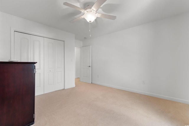 unfurnished bedroom with a closet, ceiling fan, baseboards, and light colored carpet