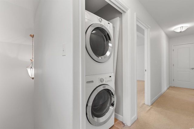 laundry room with baseboards, stacked washer / drying machine, laundry area, and light colored carpet