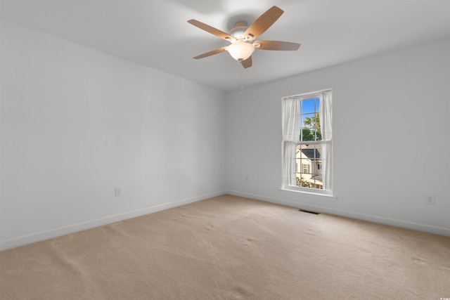 spare room featuring baseboards, ceiling fan, visible vents, and light carpet