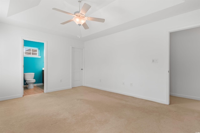 unfurnished bedroom featuring light carpet, baseboards, and ensuite bath