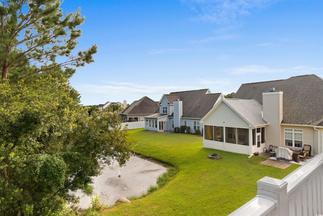 back of property with a fenced backyard, a chimney, a sunroom, and a lawn