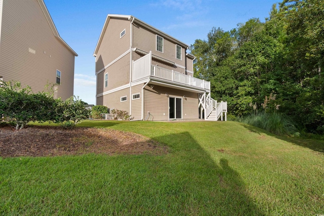 back of property featuring stairway, a deck, and a lawn