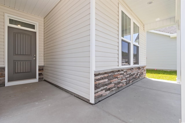 view of exterior entry with stone siding and a porch