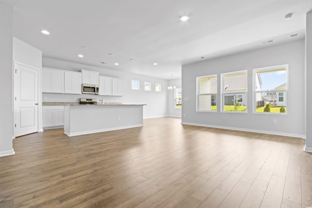 unfurnished living room featuring baseboards, visible vents, wood finished floors, and recessed lighting