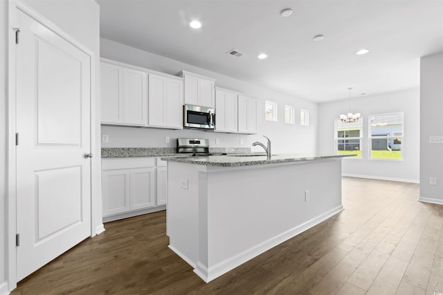 kitchen with dark wood finished floors, a center island with sink, visible vents, appliances with stainless steel finishes, and white cabinets