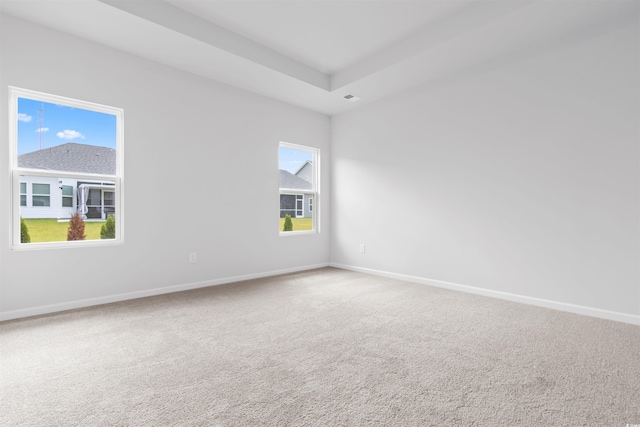 unfurnished room featuring a raised ceiling, carpet flooring, visible vents, and baseboards