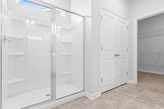 bathroom featuring a spacious closet, a stall shower, and tile patterned floors