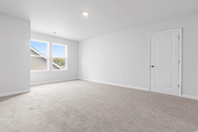 empty room featuring carpet, visible vents, and baseboards