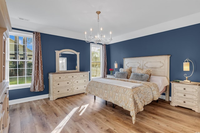 bedroom with baseboards, light wood finished floors, visible vents, and an inviting chandelier