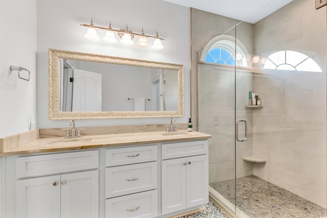 full bathroom with double vanity, a shower stall, and a sink