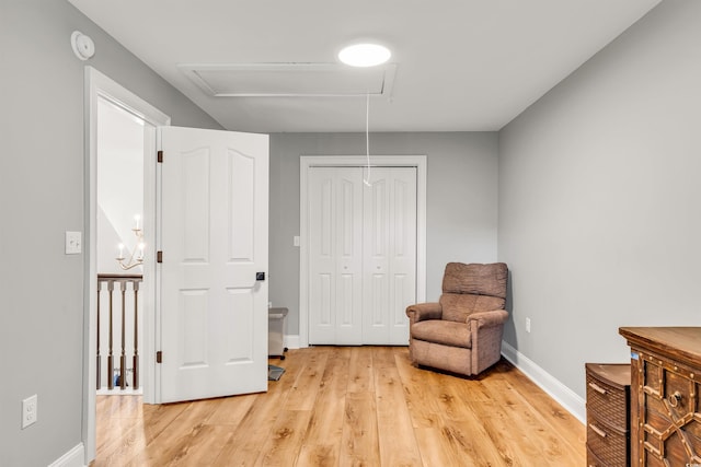 sitting room featuring baseboards, attic access, and light wood-style floors