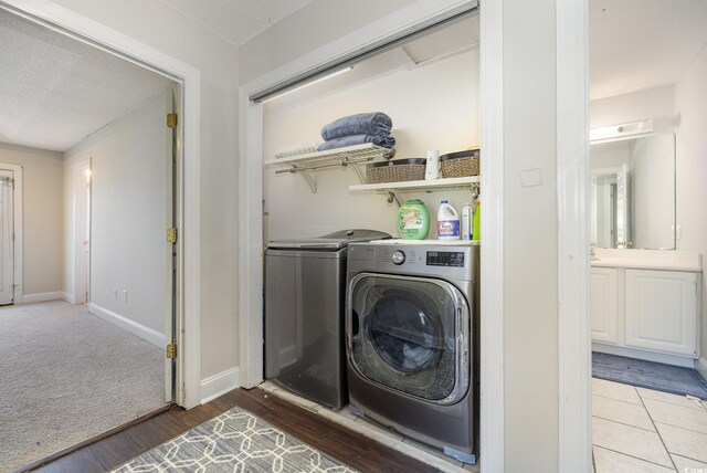 laundry room featuring a textured ceiling, wood-type flooring, and washer and clothes dryer