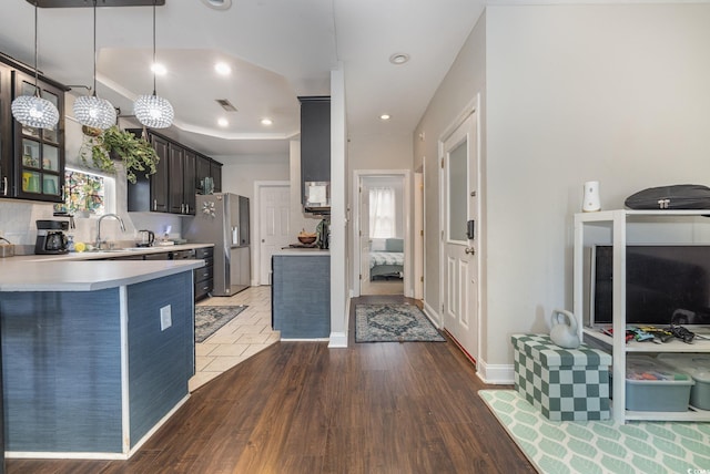 kitchen with sink, dark brown cabinetry, pendant lighting, dark hardwood / wood-style floors, and stainless steel refrigerator with ice dispenser