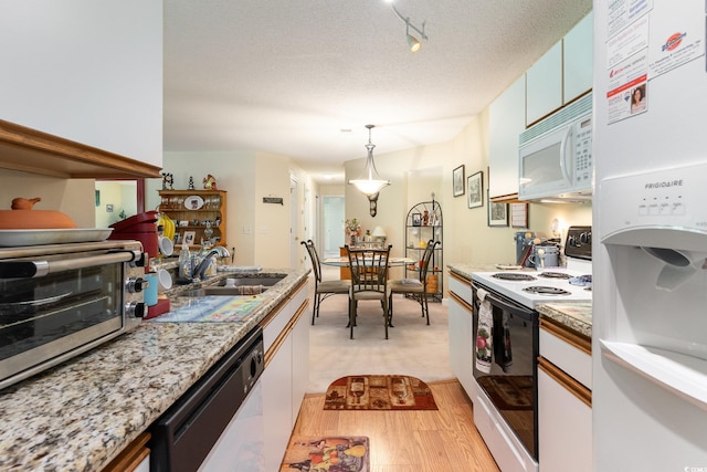kitchen with white appliances, light countertops, white cabinetry, a textured ceiling, and a sink