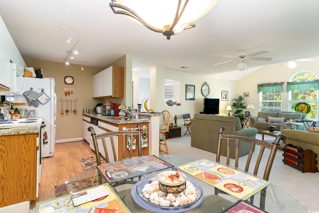dining room featuring light wood finished floors, track lighting, ceiling fan, and lofted ceiling