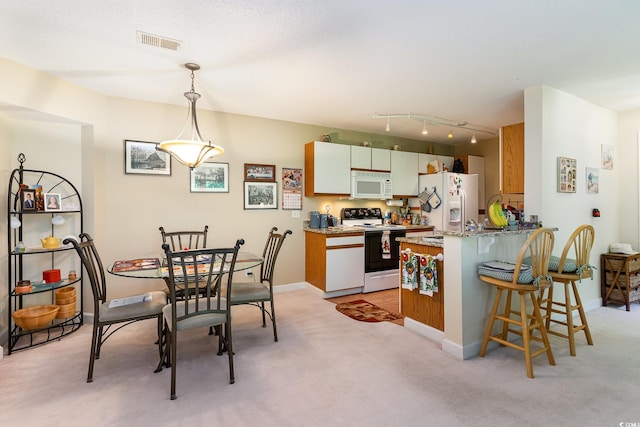 kitchen with white appliances, kitchen peninsula, light stone countertops, decorative light fixtures, and light carpet