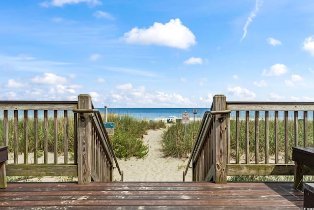 wooden deck featuring a water view and a beach view