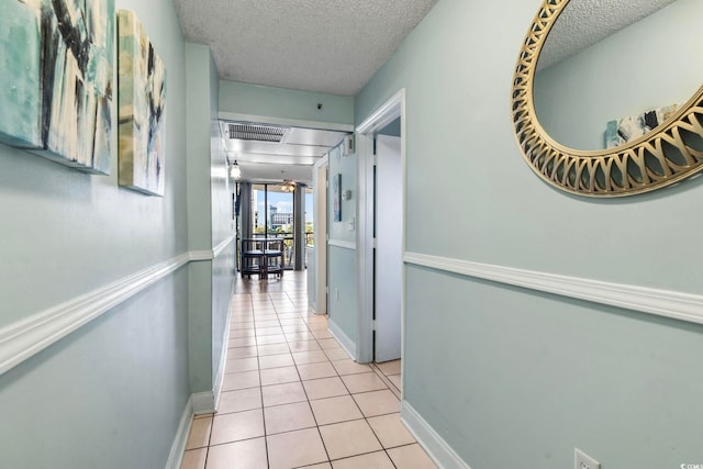 hallway featuring a textured ceiling and light tile patterned floors