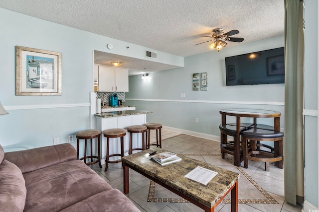 living room featuring light tile patterned floors, a textured ceiling, and ceiling fan