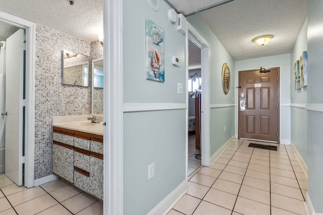 interior space featuring a textured ceiling, tile walls, sink, and light tile patterned floors