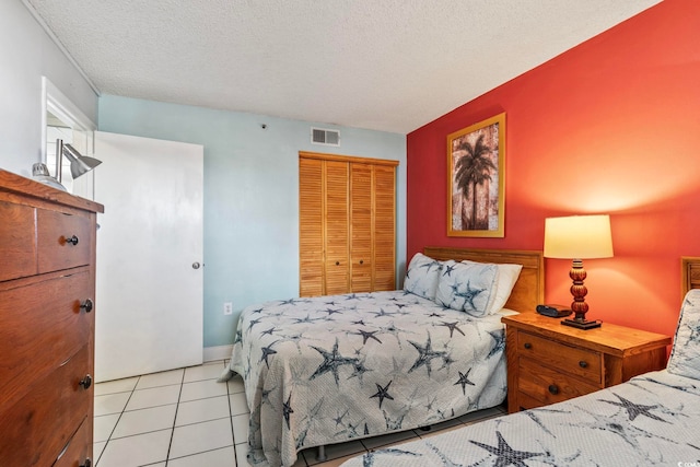 tiled bedroom with a closet and a textured ceiling