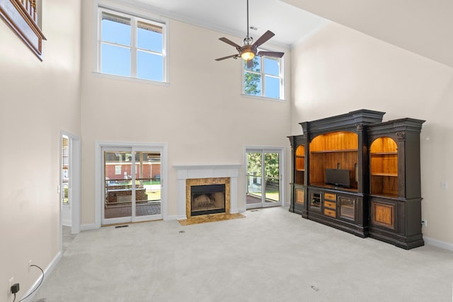 living room with a premium fireplace, a high ceiling, light carpet, and a healthy amount of sunlight