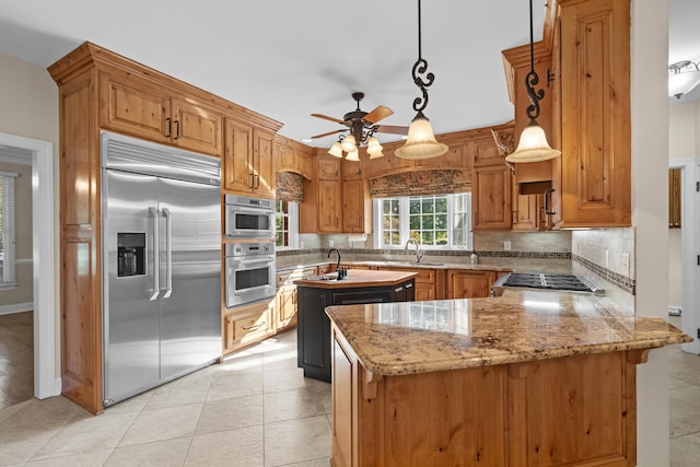 kitchen with kitchen peninsula, decorative backsplash, hanging light fixtures, appliances with stainless steel finishes, and sink