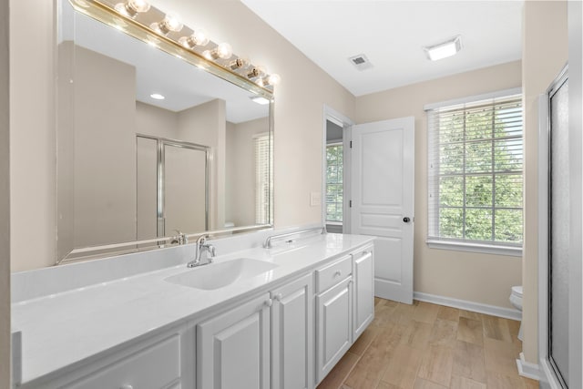 bathroom featuring vanity, a shower with shower door, hardwood / wood-style floors, and toilet