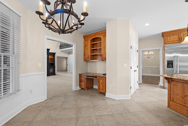 kitchen featuring pendant lighting, light stone countertops, a chandelier, and built in fridge