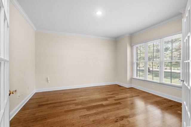 empty room with crown molding, wood-type flooring, and plenty of natural light