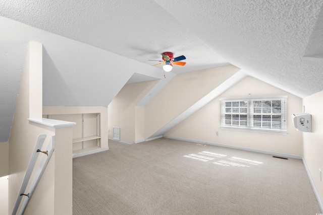 bonus room featuring vaulted ceiling, light carpet, a textured ceiling, and ceiling fan