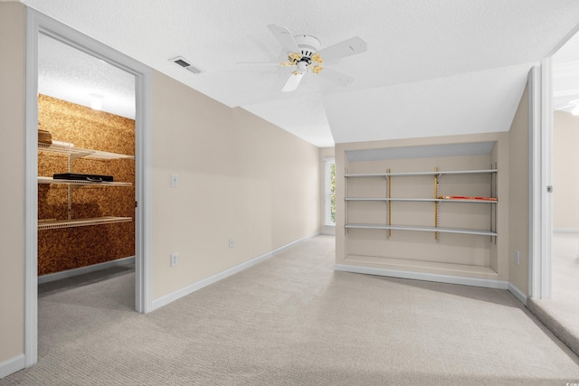 carpeted empty room with vaulted ceiling, a textured ceiling, and ceiling fan