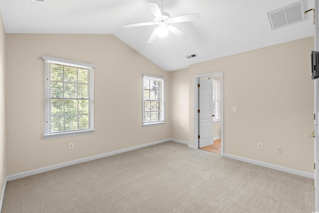 spare room featuring lofted ceiling, light colored carpet, a healthy amount of sunlight, and ceiling fan