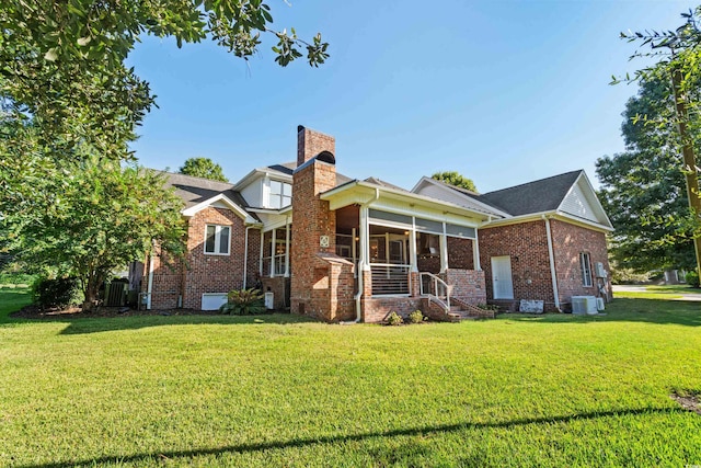 view of front of home featuring a sunroom, a front lawn, and central AC unit