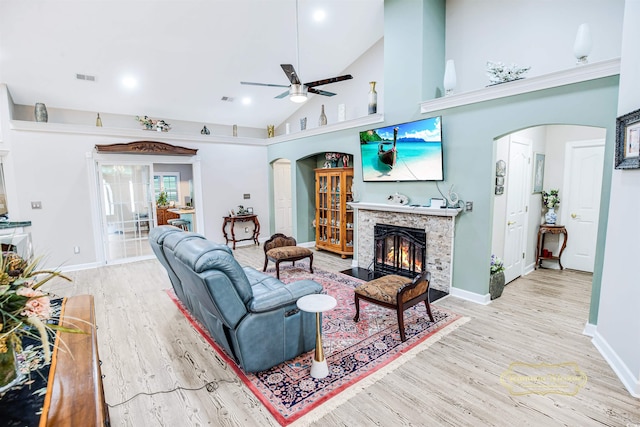 living room featuring light wood-type flooring, a fireplace, ceiling fan, and high vaulted ceiling