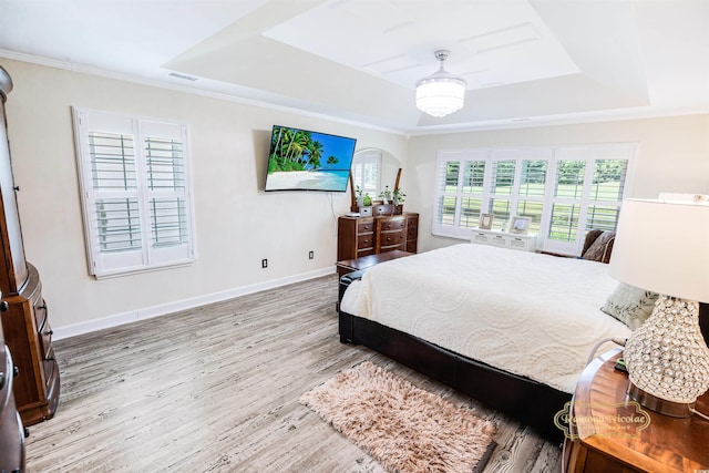 bedroom featuring light hardwood / wood-style flooring, a raised ceiling, and ornamental molding