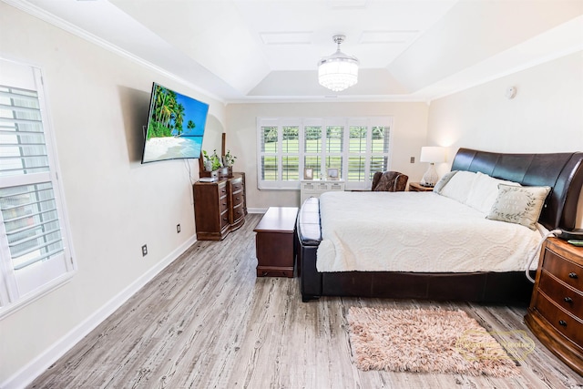 bedroom featuring crown molding, light hardwood / wood-style floors, a tray ceiling, and an inviting chandelier