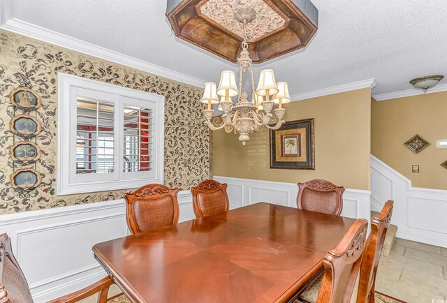 dining room with an inviting chandelier, a textured ceiling, crown molding, and light tile patterned flooring