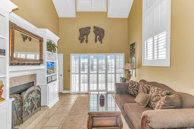 living room with a high ceiling, a healthy amount of sunlight, a fireplace, and light tile patterned flooring