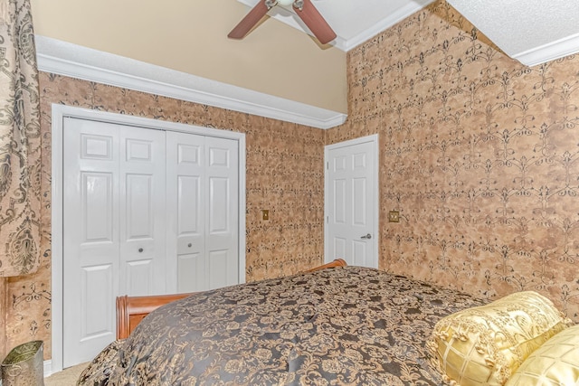 carpeted bedroom with ornamental molding, a closet, ceiling fan, and a textured ceiling