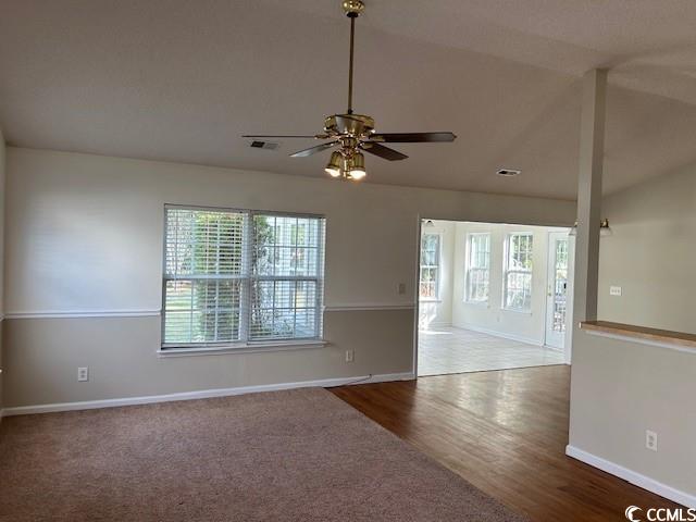 empty room with ceiling fan, hardwood / wood-style floors, and lofted ceiling