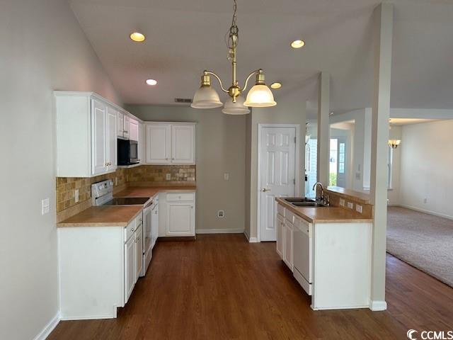 kitchen with white appliances, an inviting chandelier, white cabinetry, and dark wood-type flooring