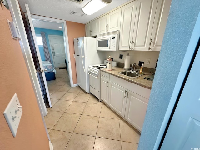 kitchen featuring white cabinets, light tile patterned floors, sink, white appliances, and a textured ceiling