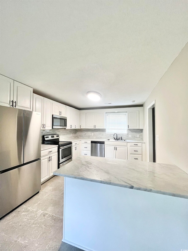 kitchen featuring tasteful backsplash, white cabinets, stainless steel appliances, a textured ceiling, and sink