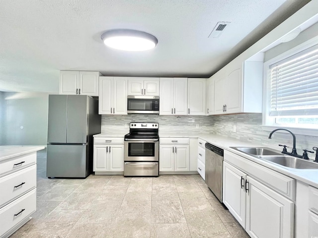 kitchen featuring white cabinets, appliances with stainless steel finishes, sink, and tasteful backsplash