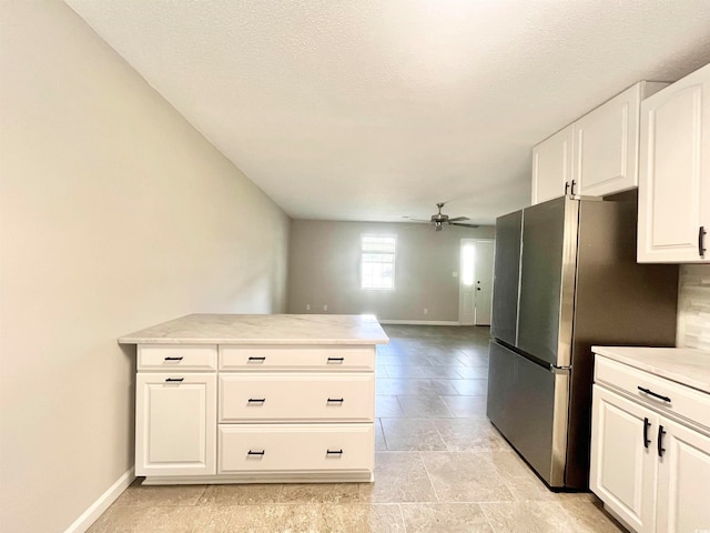 kitchen with white cabinets, stainless steel refrigerator, kitchen peninsula, a textured ceiling, and ceiling fan