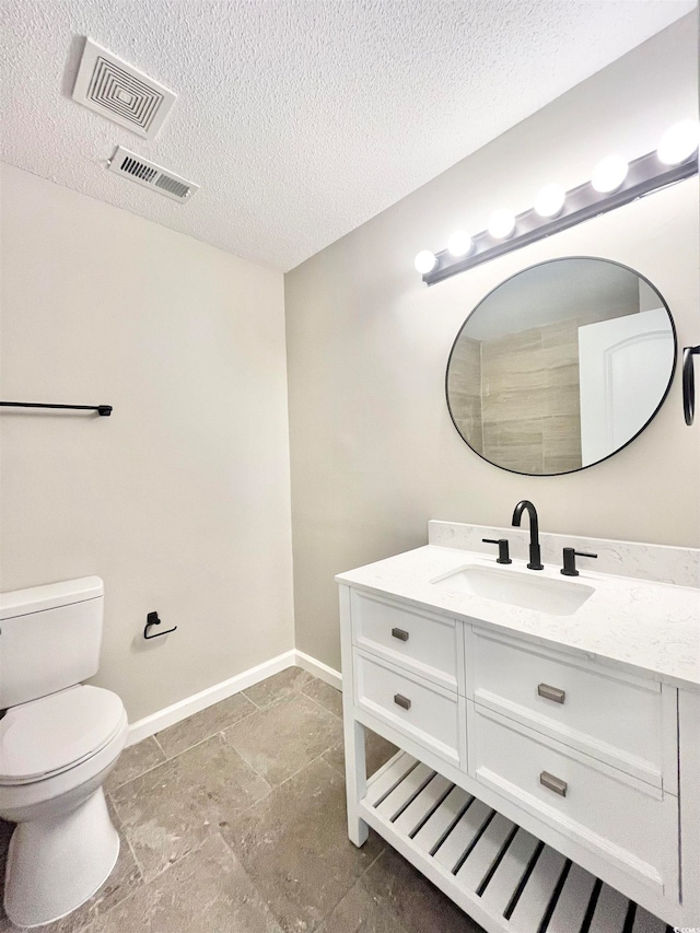 bathroom featuring a textured ceiling, vanity, and toilet