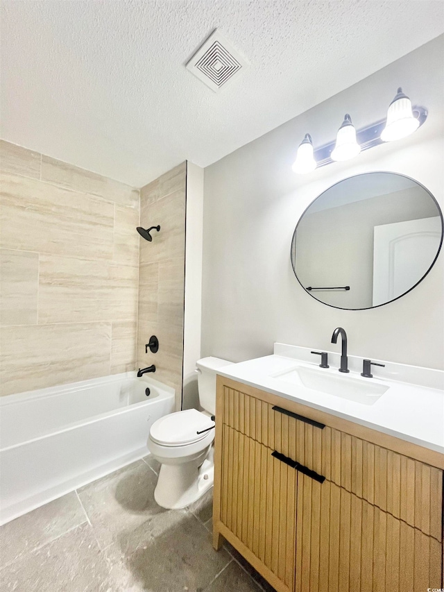 full bathroom featuring a textured ceiling, tiled shower / bath combo, vanity, and toilet