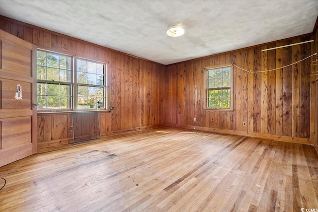 empty room with wood walls and light hardwood / wood-style flooring