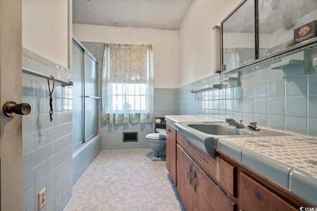 full bathroom featuring vanity, enclosed tub / shower combo, tile walls, and toilet